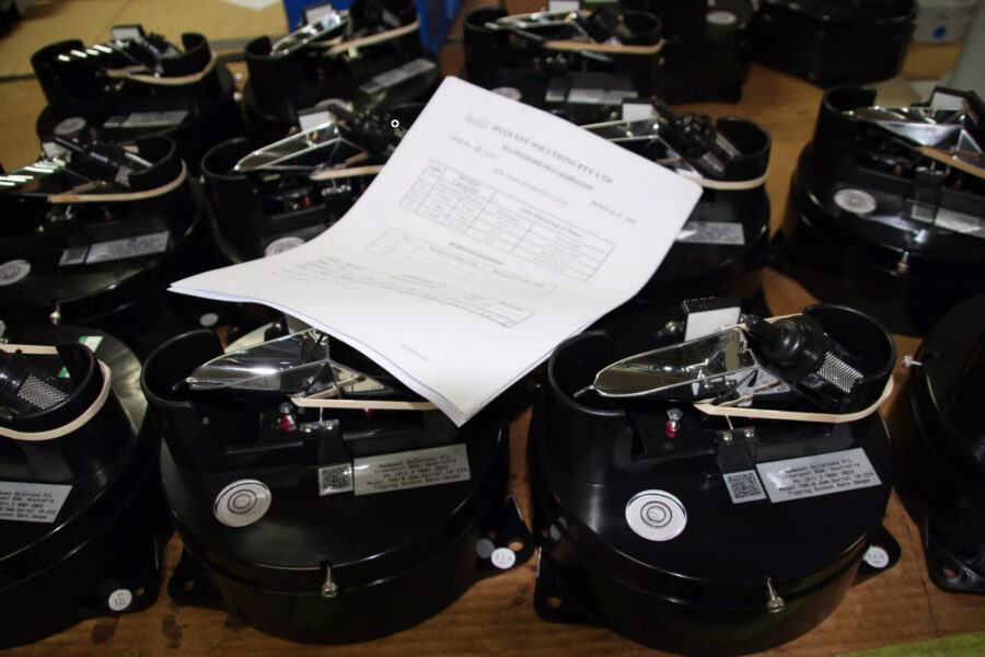 Several black mechanical devices are arranged on a table, providing instruments support, with a sheet of paper containing a printed form or chart resting on top. The devices have metallic components and buttons.