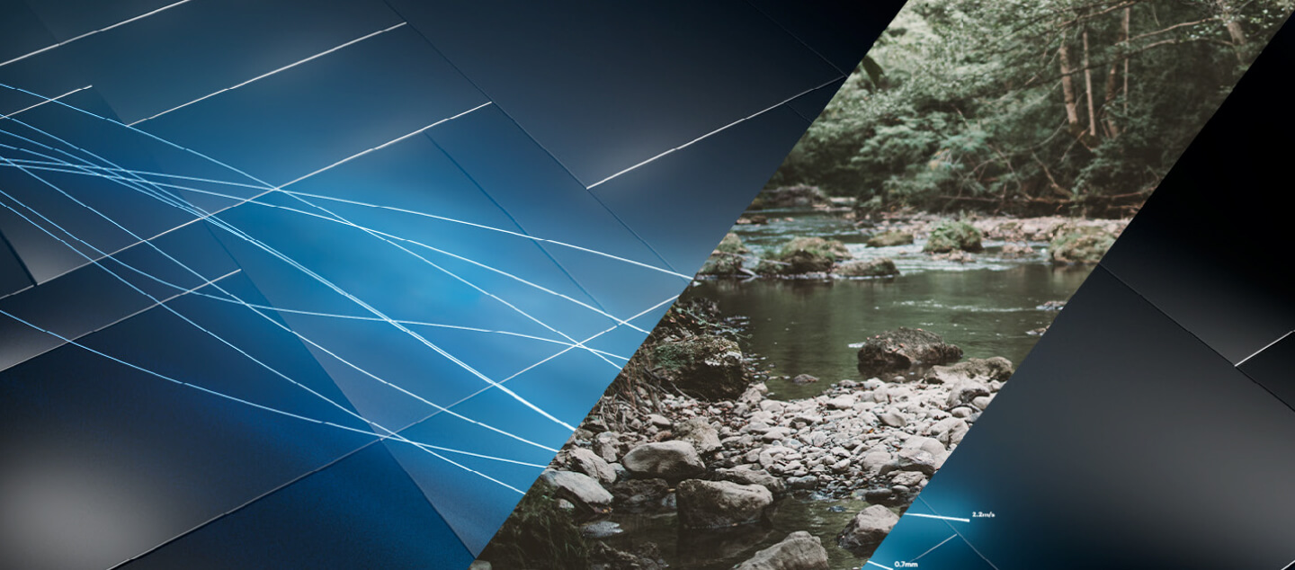 Abstract image with intersecting metallic blue and black panels, featuring a diagonal section displaying a forest stream with rocks and green trees. Light blue lines cross the panels, adding a dynamic effect.